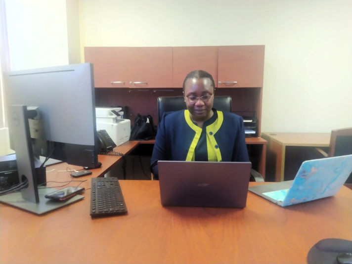 Black woman sitting at desk in business attire.