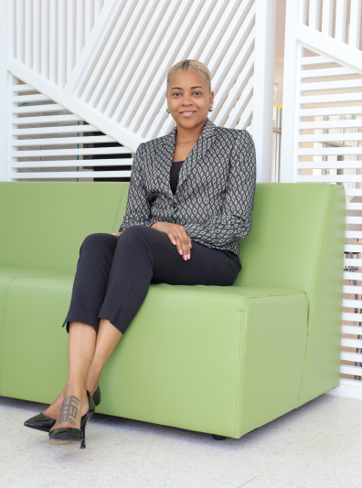 Black woman in business attire on lime green lounge chair.